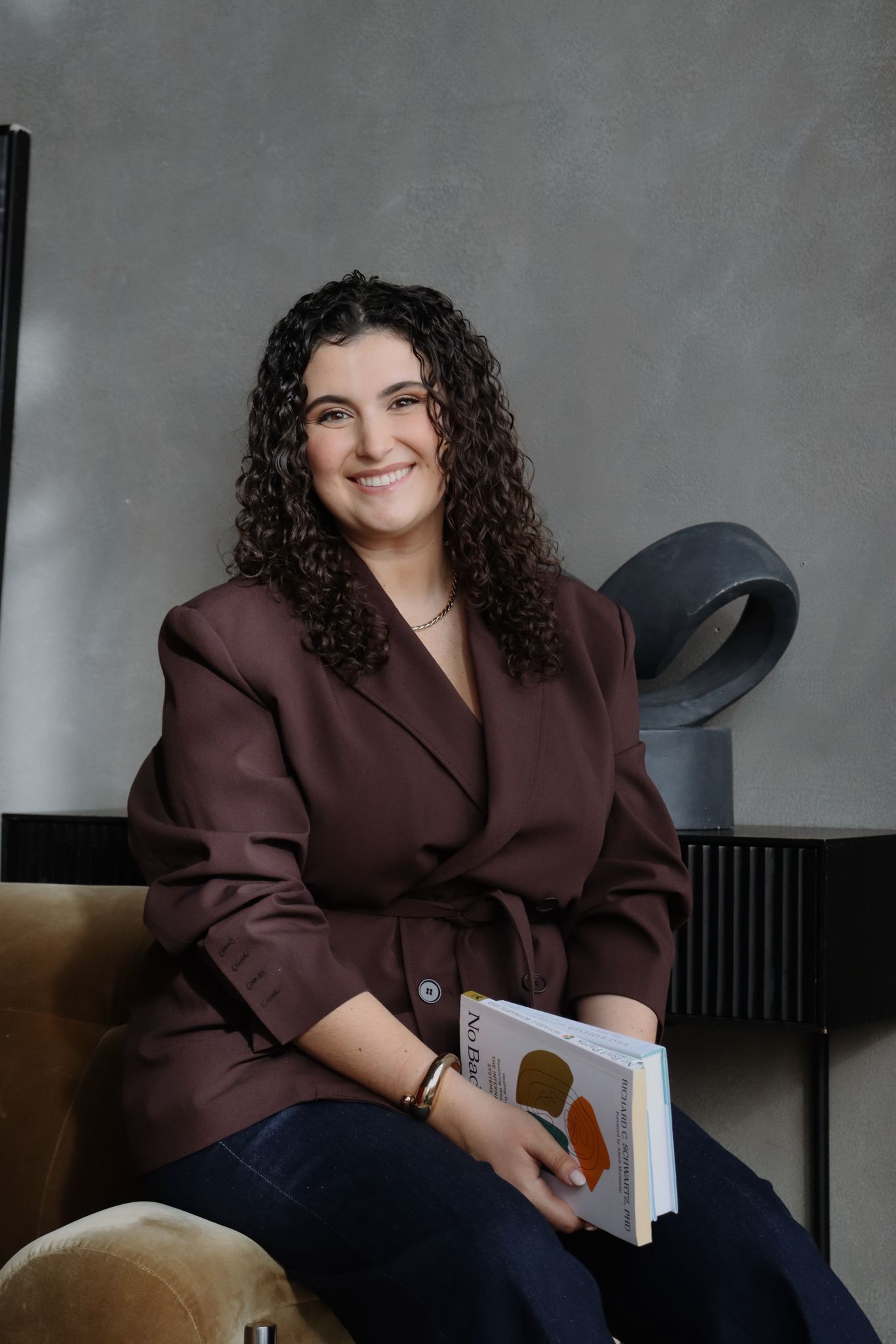 Shir sitting with book, brown blazer